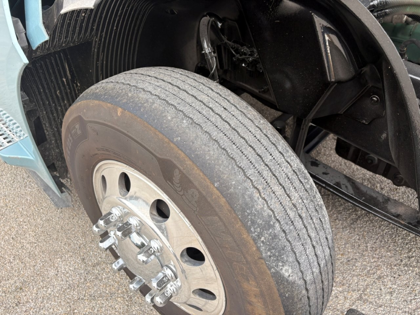 Volvo VNL64T760 truck front wheel showing dual rear? front tire with steel wheel and five-lug hub; visible tire tread, wheel bolts, and part of the fender; no legible model text visible.