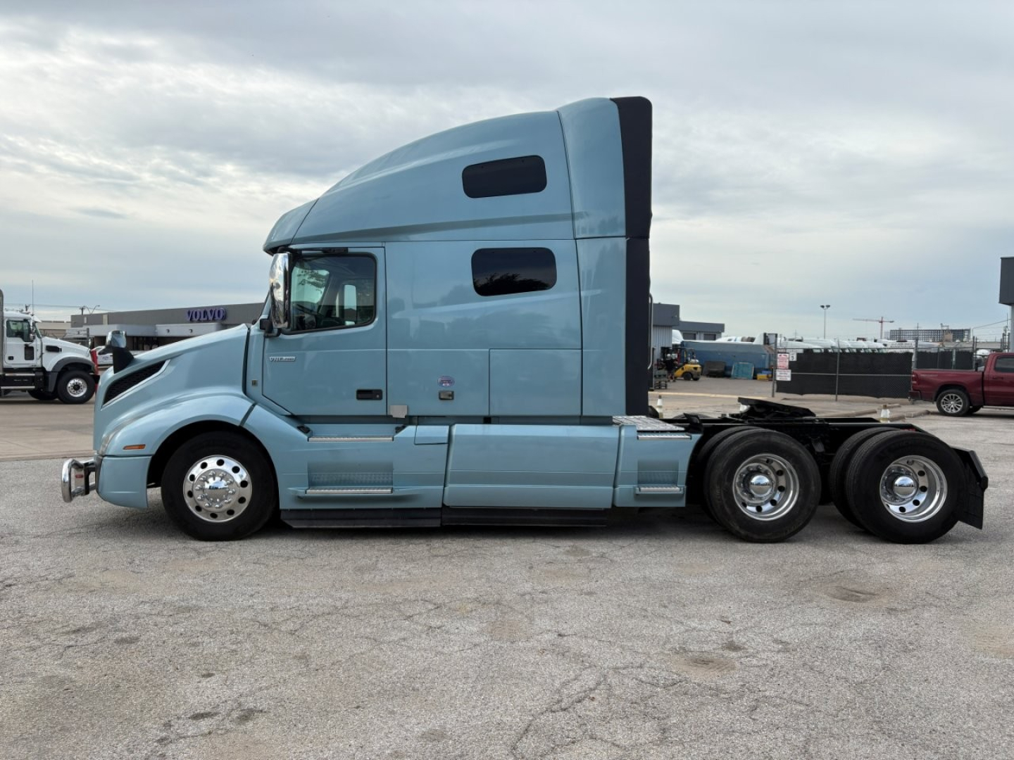 Volvo VNL64T760 tractor-trailer side view showing sleeper cab, chrome wheels, and fuel tanks.