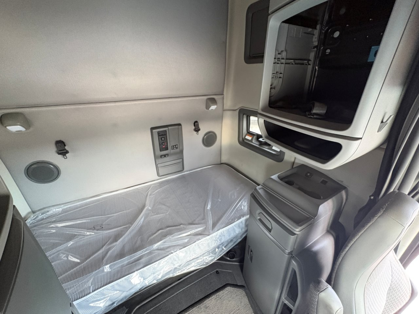 Volvo VNL64T760 truck sleeper cab interior showing bunk bed with plastic cover, side panels, and storage compartment.