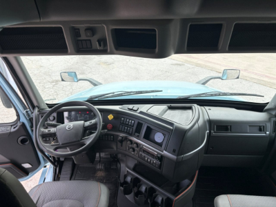 Cab interior of a Volvo VNL64T760 truck showing steering wheel, dashboard, and control panels in the driver’s area.