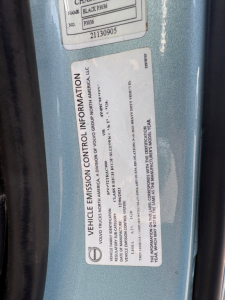 Vehicle emission control information label on Volvo VNL64T760 showing federal EPA details and VIN-4V4NC9EH9NN605505 with a blue truck door frame.