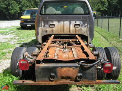 Cab and chassis rear view showing rusted frame rails and dual rear tires with taillights.
