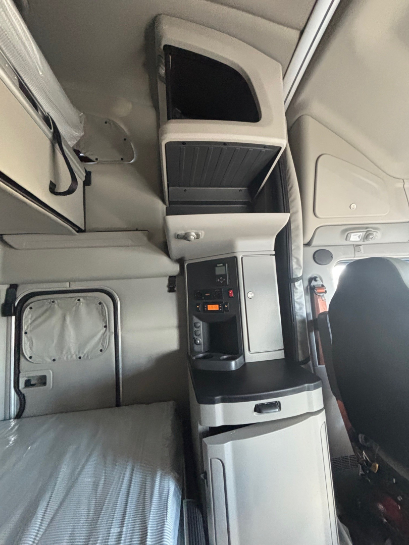 Cab interior of a 2022 Peterbilt 579 showing the dashboard console, storage compartments, and sleeper area with compartments and seating visible.