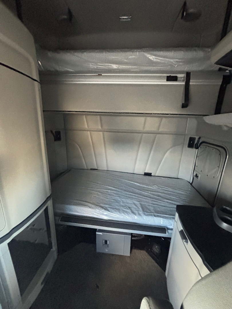 Peterbilt 579 sleeper cab interior showing bunk area with mattress, side cabinets, and overhead storage.