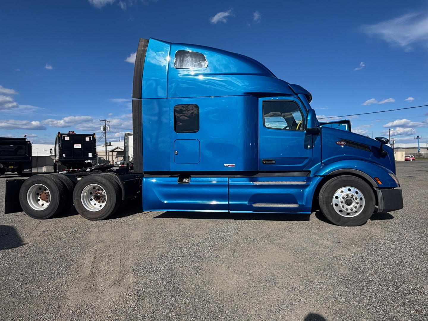 Peterbilt 579 tractor cab in blue, side profile view, shows sleeper compartment and chrome wheels, no visible text on panels.