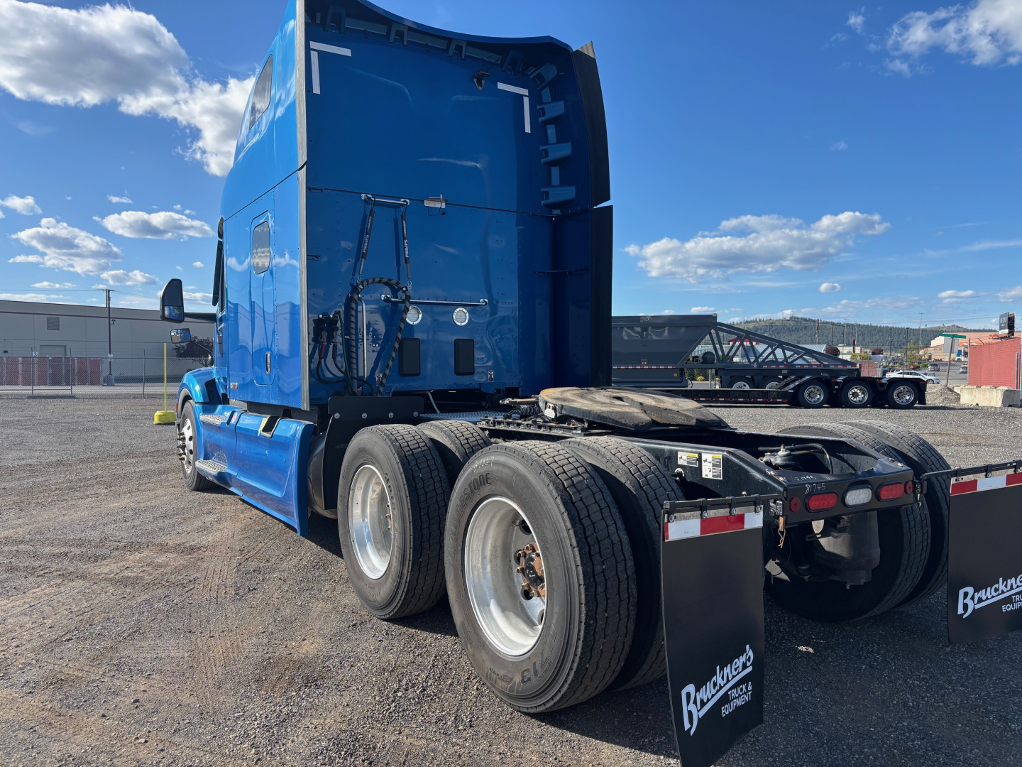Peterbilt 579 heavy-duty truck tractor rear triple axle view, blue cab, sleeper, fuel tanks and wheels visible; no legible labels or text on the visible surfaces.