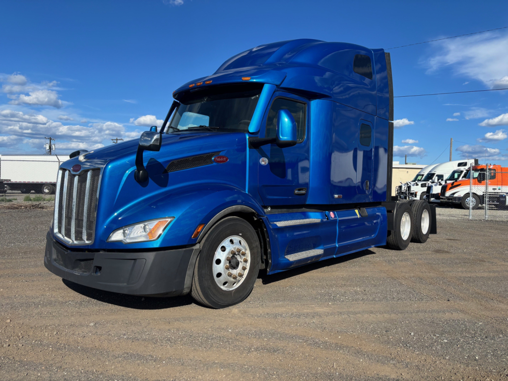 Peterbilt 579 tractor with blue exterior, sleeper cab, front perspective.
