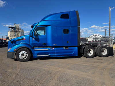 Peterbilt 579 tractor in blue, side view showing sleeper cab, rear axle group, and fuel tanks.