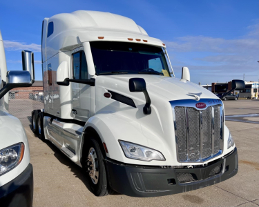 Peterbilt 579 highway tractor in white, front three-quarter view with chrome grille, side mirrors, and sleeper cab.