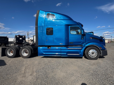 Peterbilt 579 tractor cab in blue, side profile view, shows sleeper compartment and chrome wheels, no visible text on panels.