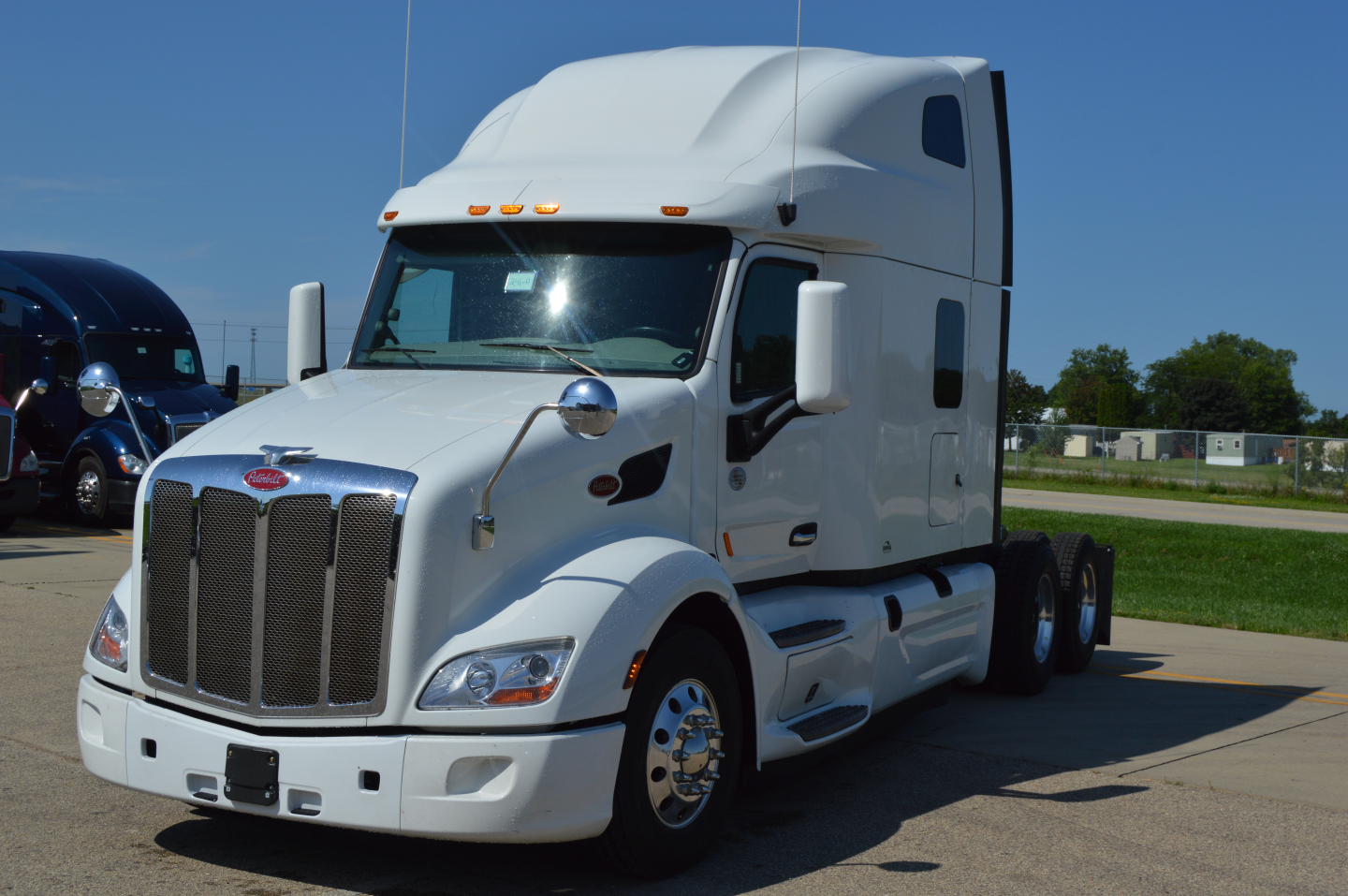 Peterbilt 579 tractor-trailer cab in front view showing aerodynamic hood and grille, white exterior, sleeper cab, dual rear axles