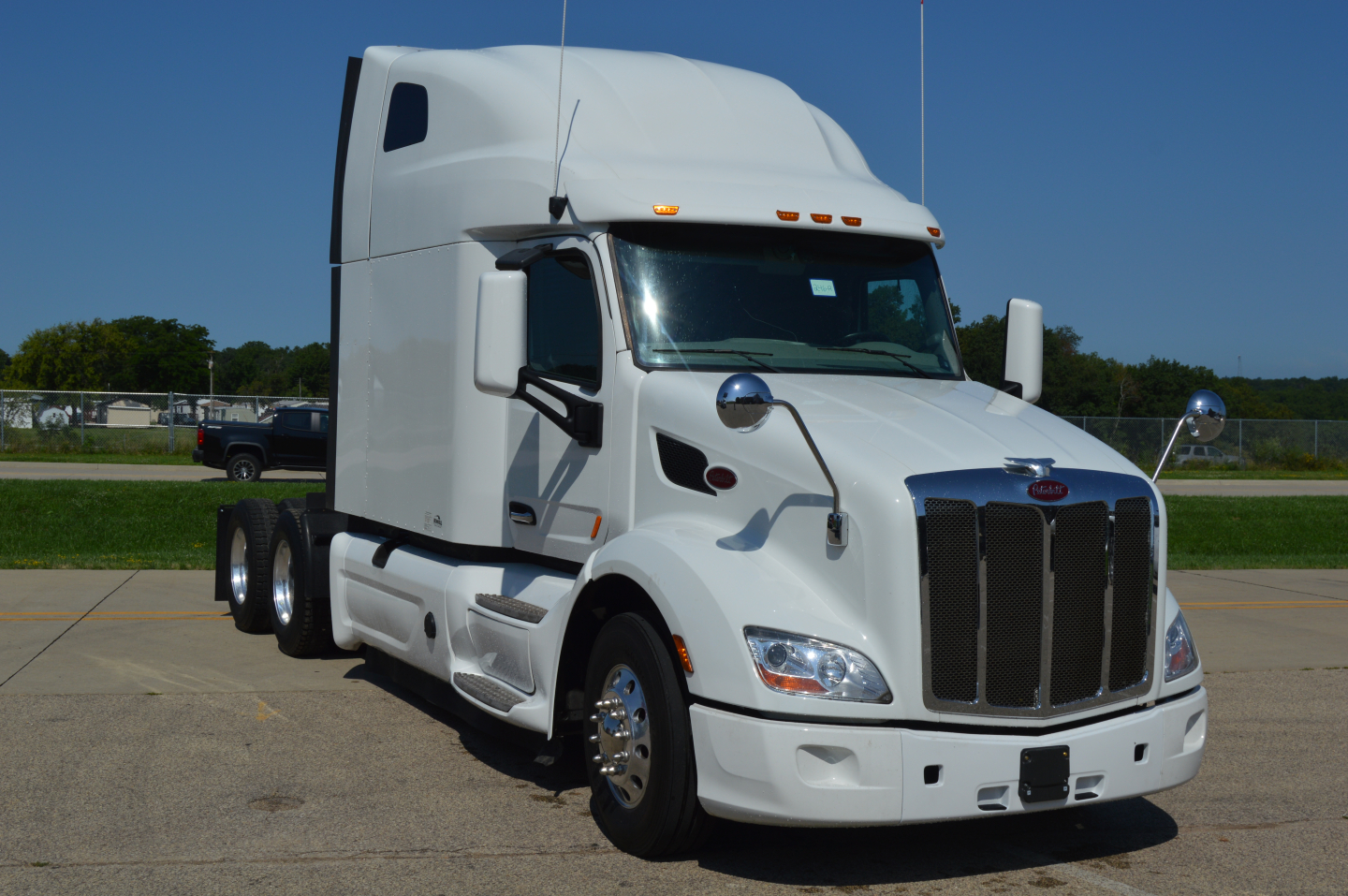 Peterbilt 579 truck cab front view with white exterior and chrome grille; visible text on sticker near windshield shows VIN and stock number not legible; no other readable labels.
