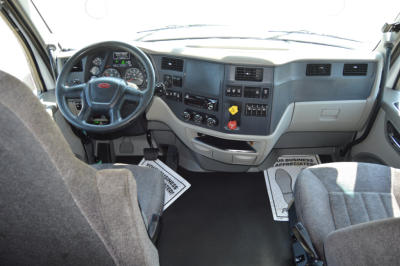 Peterbilt truck cab interior showing dashboard, steering wheel, and two front seats.