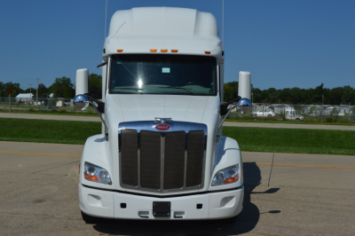 Peterbilt 579 front view showing large black grille, chrome mirrors, and white exterior; headlights visible.