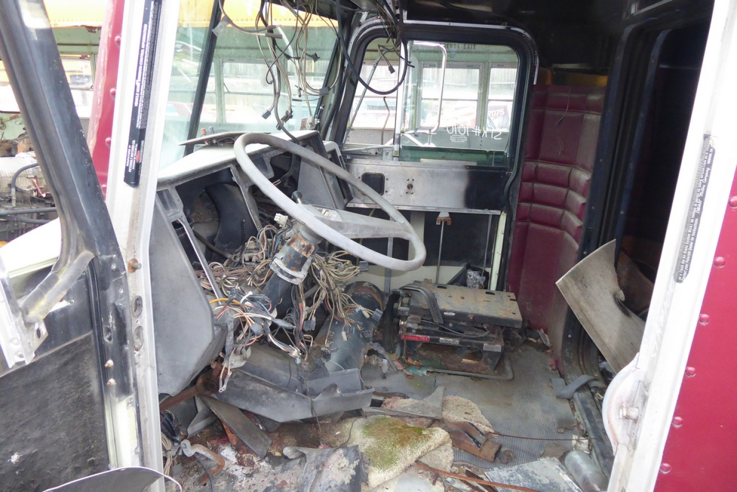 Interior of a 1988 Peterbilt 379 cab showing exposed wiring and steering column, front dash area with tangled wires and debris on the floor.