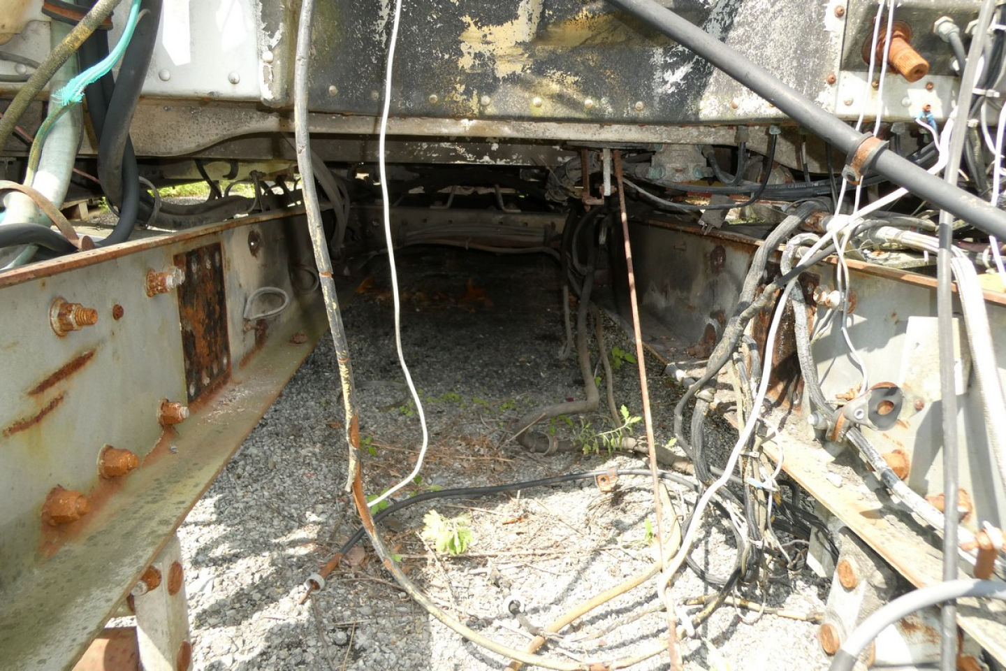 Peterbilt truck chassis interior under cab with exposed rails, wiring, and rusted metal components.