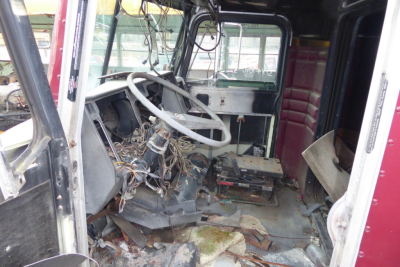 Interior of a 1988 Peterbilt 379 cab showing exposed wiring and steering column, front dash area with tangled wires and debris on the floor.