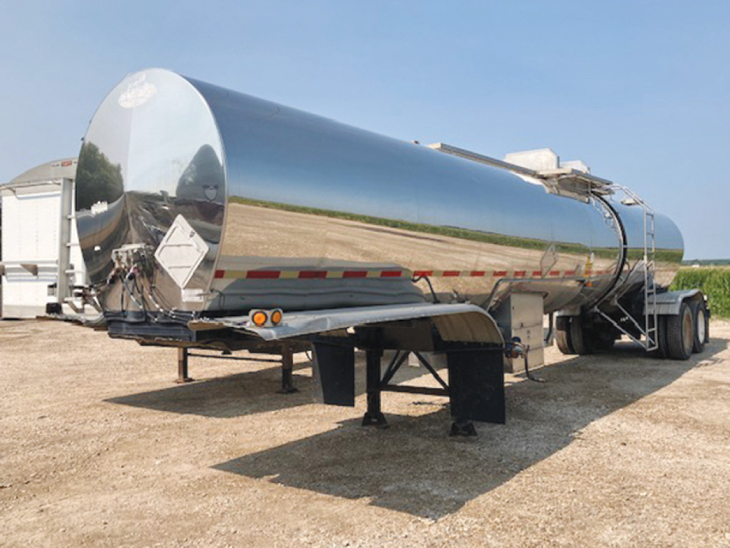 Trailer tanker with polished stainless steel cylindrical tank on dual rear axles and support legs, viewed from side, labeled as Polar tanker equipment.