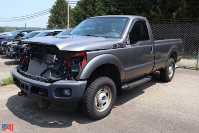 Ford F-250 Super Duty pickup truck with front-end damage showing open hood area and exposed radiator, gray two-door cab, long bed, (2012 model) in a used vehicle lot.