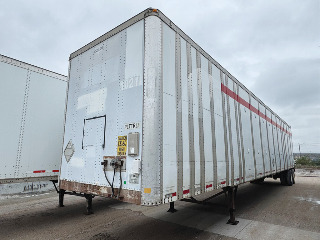 Trailer side view showing a Wabash dry van trailer with DuraPlate panels and a side door, registration placard near rear, landing legs down.