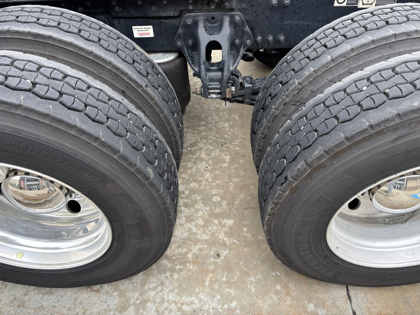 Dual rear wheels of a 2023 Kenworth T680 truck showing tires and axle assembly.