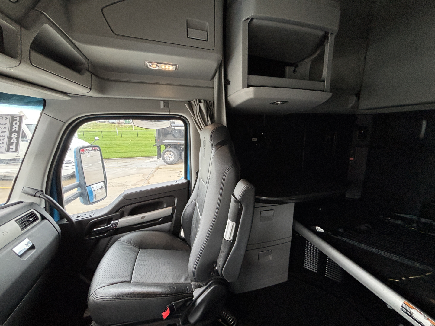 Kenworth T680 truck interior cab view showing driver seat and overhead storage.