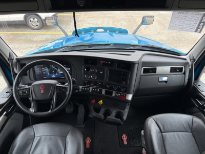 Kenworth T680 cab interior with steering wheel, dashboard gauges, and center console, driver and passenger seats visible.
