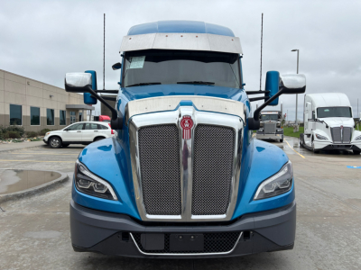 Kenworth T680 front view showing bold chrome grille and blue cab; front bumper with black lower section and mesh air intake.