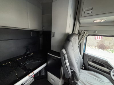 Kenworth T680 truck interior cab view focusing on driver seat and sleeper area with overhead cabinets and dashboard.