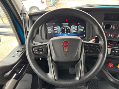 Steering wheel and instrument cluster of a Kenworth T680 truck interior showing dashboard gauges and steering wheel emblem.