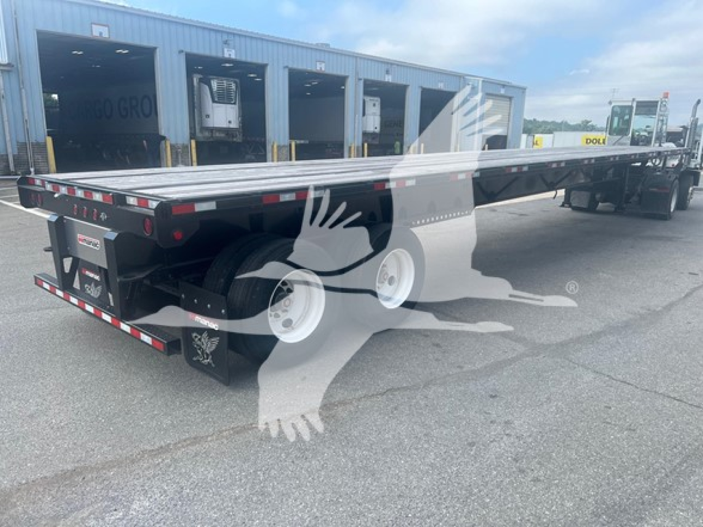 Manac spring extendable flatbed trailer in view showing rear and side rails with black and silver finish.