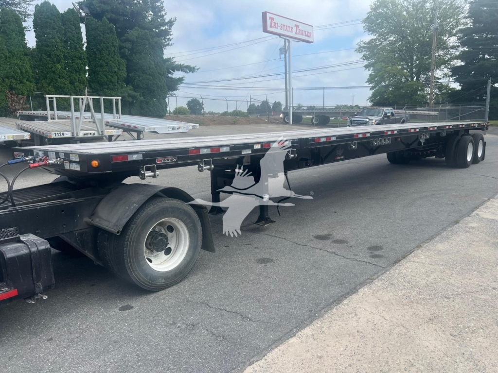 Manac flatbed trailer with extendable deck showing long aluminum deck, wheel sets, and winch in side view