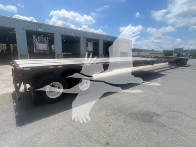 Manac extendable flatbed trailer in side view showing dual rear axles and extendable bed with reflective markings.