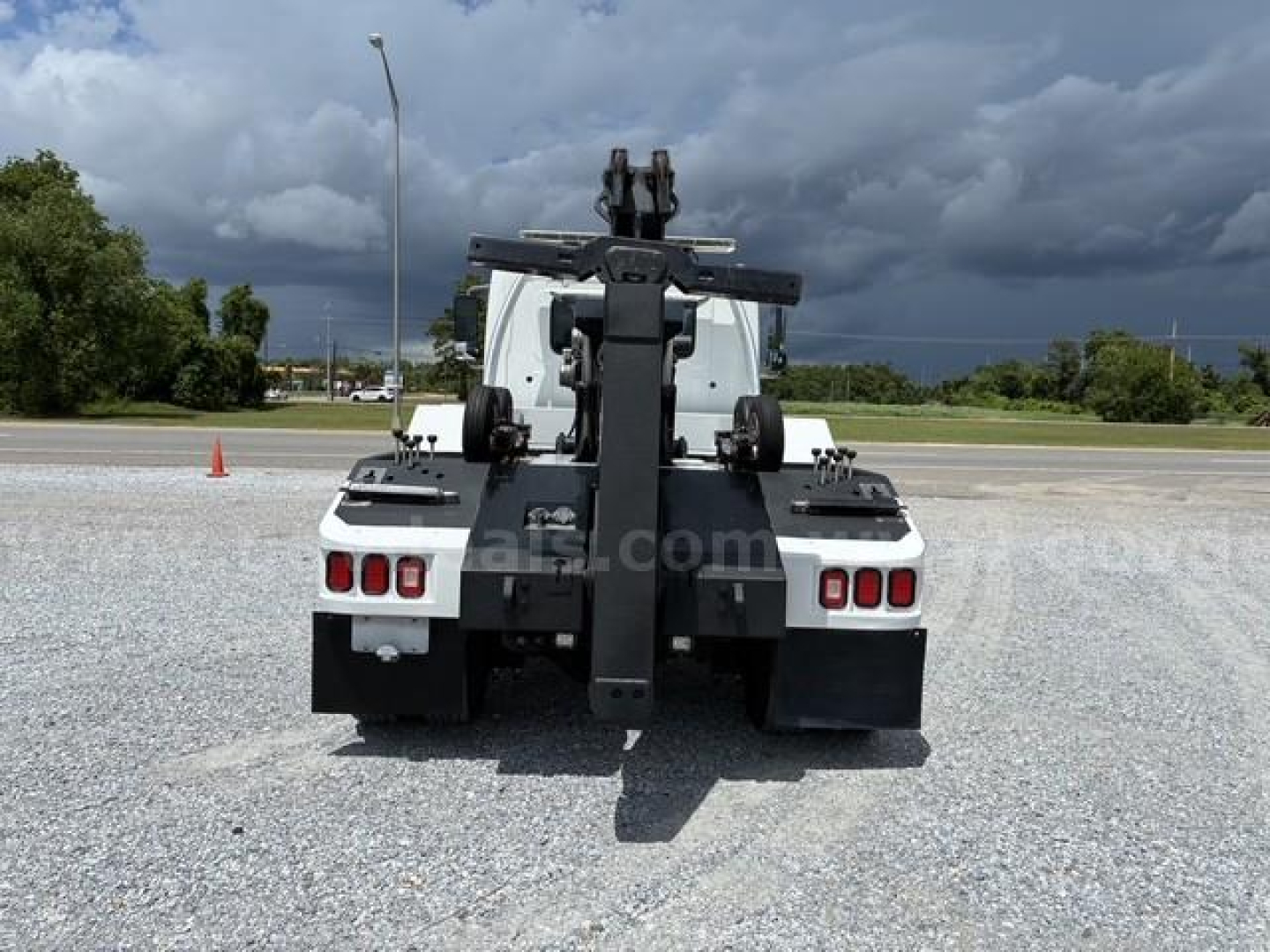 Rear view of a 2018 Hino conventional cab tow truck with a heavy-duty hitch/loader system, white chassis, black mounting frame, and rear lights visible.
