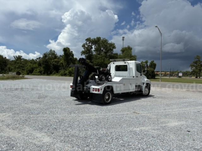 Tow truck with a flatbed in a gravel lot, 2018 Hino conventional cab, VIN visible.