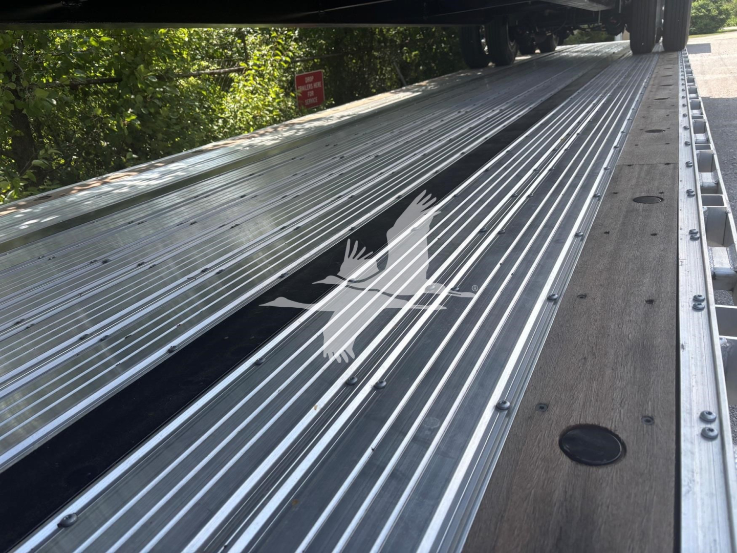 Open trailer side rail with corrugated aluminum deck and hinge mechanism visible, on a Dorsey combo drop trailer.