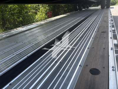 Open trailer side rail with corrugated aluminum deck and hinge mechanism visible, on a Dorsey combo drop trailer.