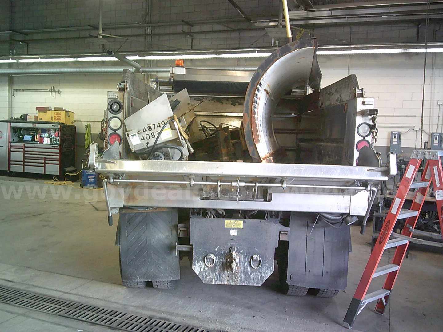 Dump truck rear showing hydraulic tailgate and spreader mechanism on International WorkStar 7400, with heavy tires and metal components.