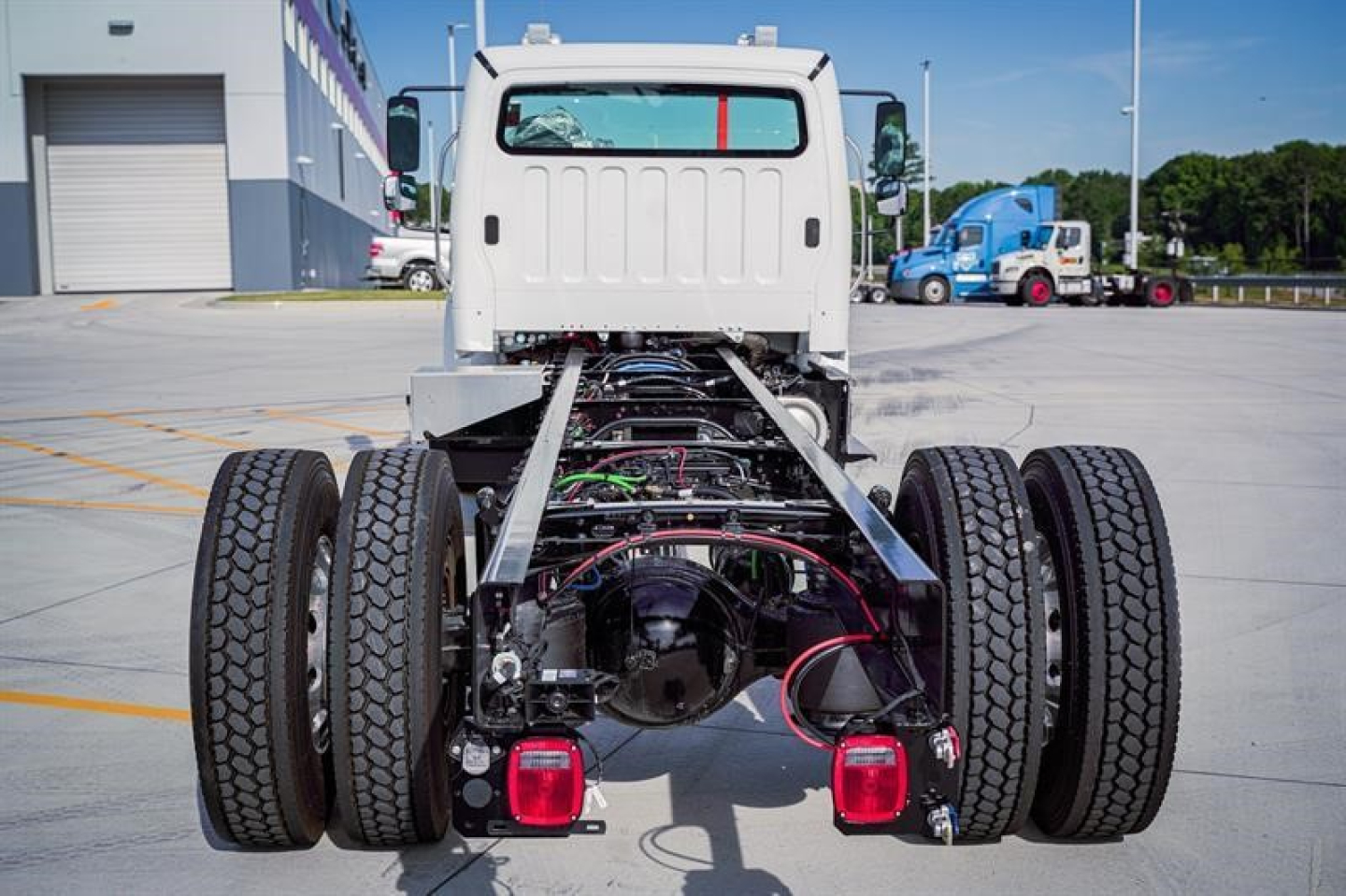 Freightliner M2 106 Plus chassis back view showing dual rear axles, fuel lines, wiring, and chassis frame.