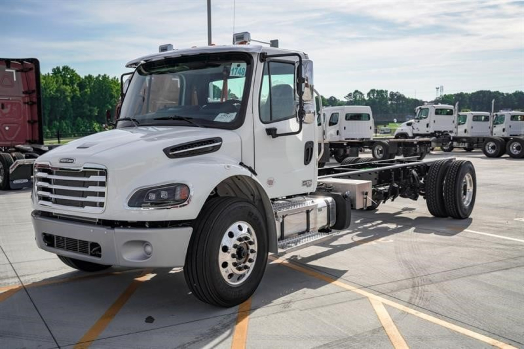 White Freightliner M2 106 Plus cab and chassis truck with extended chassis and dual rear axles, front view showing grille, headlights, and side mirrors.