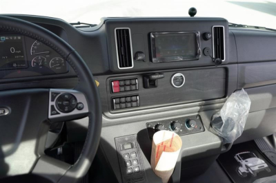 Cab interior of a Freightliner M2 106 Plus showing steering wheel, dashboard, touchscreen display, air vents, and control panel with buttons.