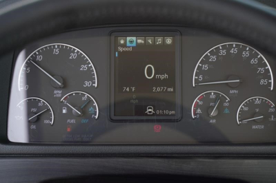 Dashboard cluster of a Freightliner M2 106 Plus showing speedo, tachometer, center digital display reading 0 mph, 74 F, 2,077 mi, time 01:10 pm.