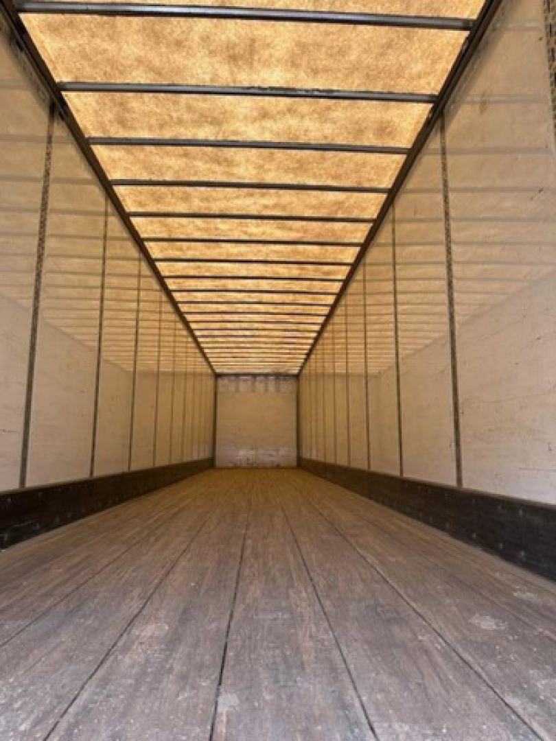 Trailer interior of a 2016 Wabash van showing empty cargo area with wooden floor and side walls; long rectangular ceiling supports visible.