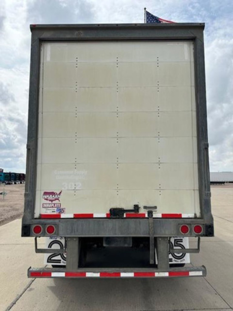 Rear view of a 2016 Wabash van trailer with blank white rear door, red and white reflective tape, and taillights along the bumper.