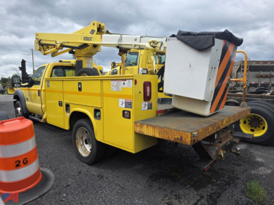 Ford F-550 bucket truck showing rear platform and aerial lift, yellow utility body with decals and hoses.
