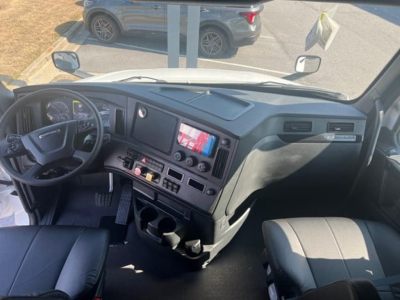 Dashboard and driver area of a Freightliner Cascadia 126 truck cabin with steering wheel, control panel, and storage compartments visible.