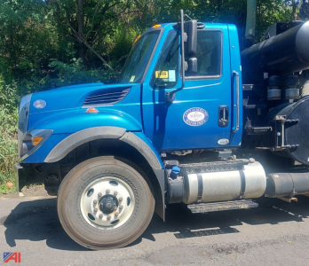 Blue 2018 International WorkStar 7500 vacuum truck side view showing cab, front wheel, exhaust stack, and vacuum tank with chrome fuel tank and badges.
