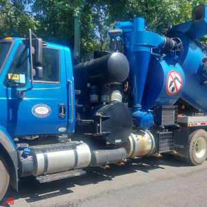 Vacuum truck side view showing blue cab and large blue vacuum tank with piping and intake on International WorkStar 7500 in service.