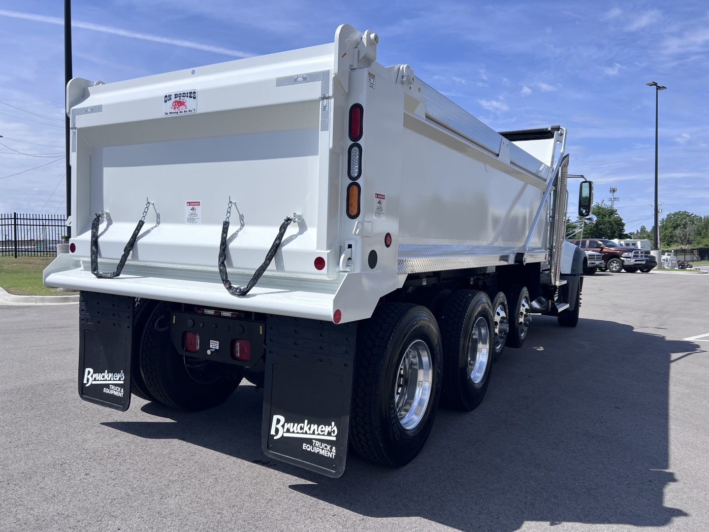 Dump truck rear three-quarters view showing rear gate, dual rear axles with six tires, and mud flaps labeled Bruckner's Equipment.