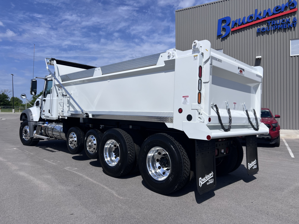 Dump truck rear and side view showing large white Mack GR64F dump body, multiple axles, chrome wheels, and heavy-duty tires.